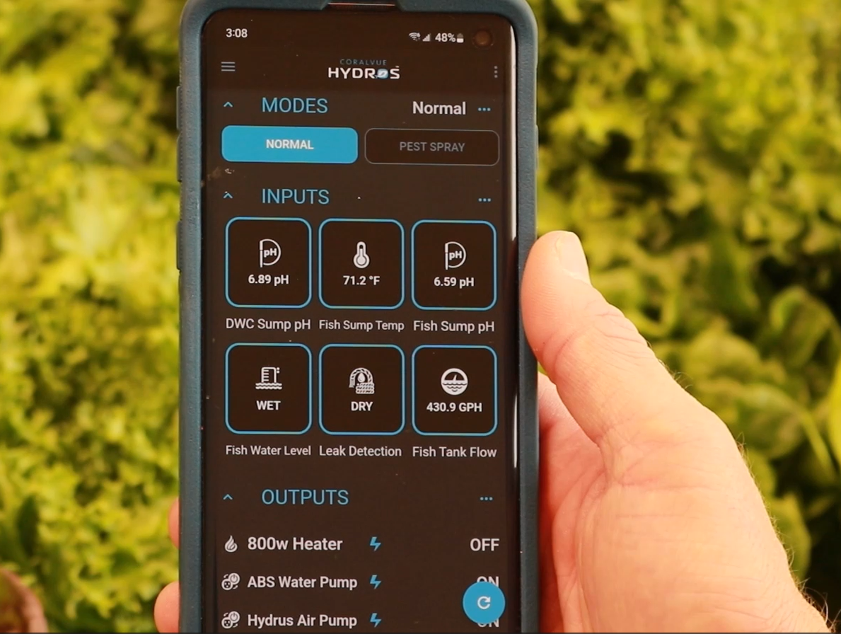 A person holding up a smartphone with a green screen and using the TAS HYDROS Rope Leak Detection Extension Cable controller.