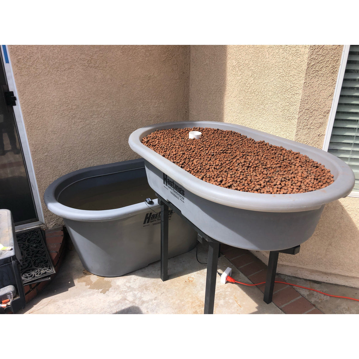 A spacious Go Green Double Aquaponics System fish tank filled with an abundant amount of gravel.