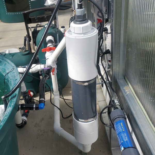 A XFLO Systems UV Sterilizer with a hose attached to it that effectively removes waterborne pathogens and post-solids through the use of UV-C light.