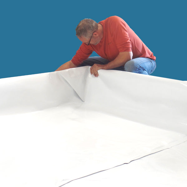 Man in red shirt smoothing out a large, tear-resistant Aquaponics For Life Dura-Skrim liner – 18′ x 50′ on a blue background.