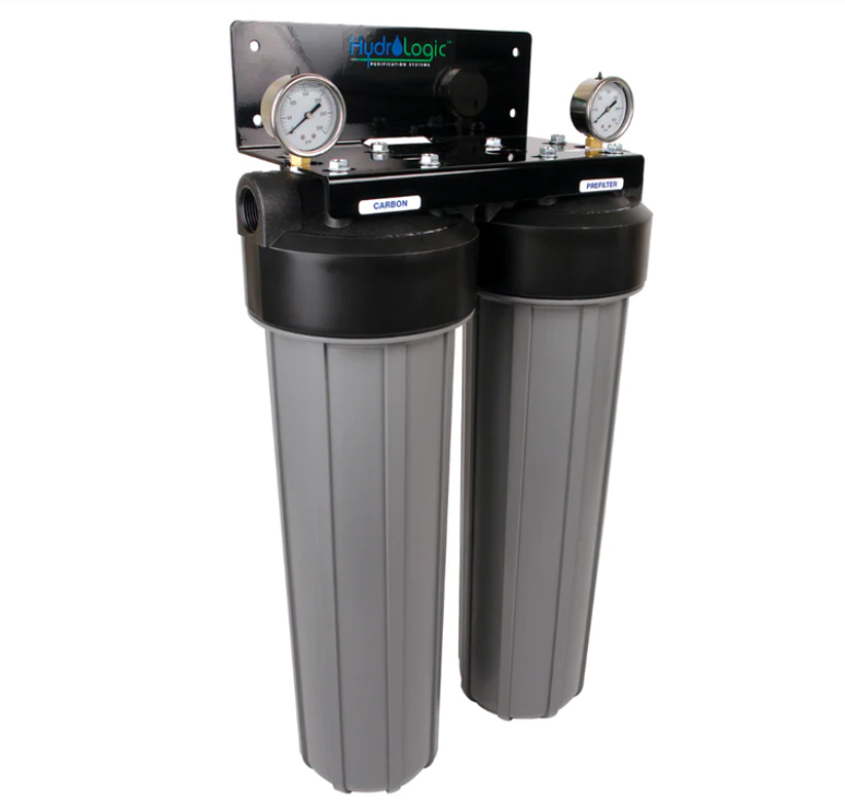 Dual-stage water filtration system with pressure gauges, labeled "Carbon" and "Sediment." Black and gray design mounted on a black bracket ensures chlorine removal for whole house application. The TAS Hydrologic Big Boy Dechlorinator & Sediment Water Filter is an excellent choice for maintaining clean water throughout your home.