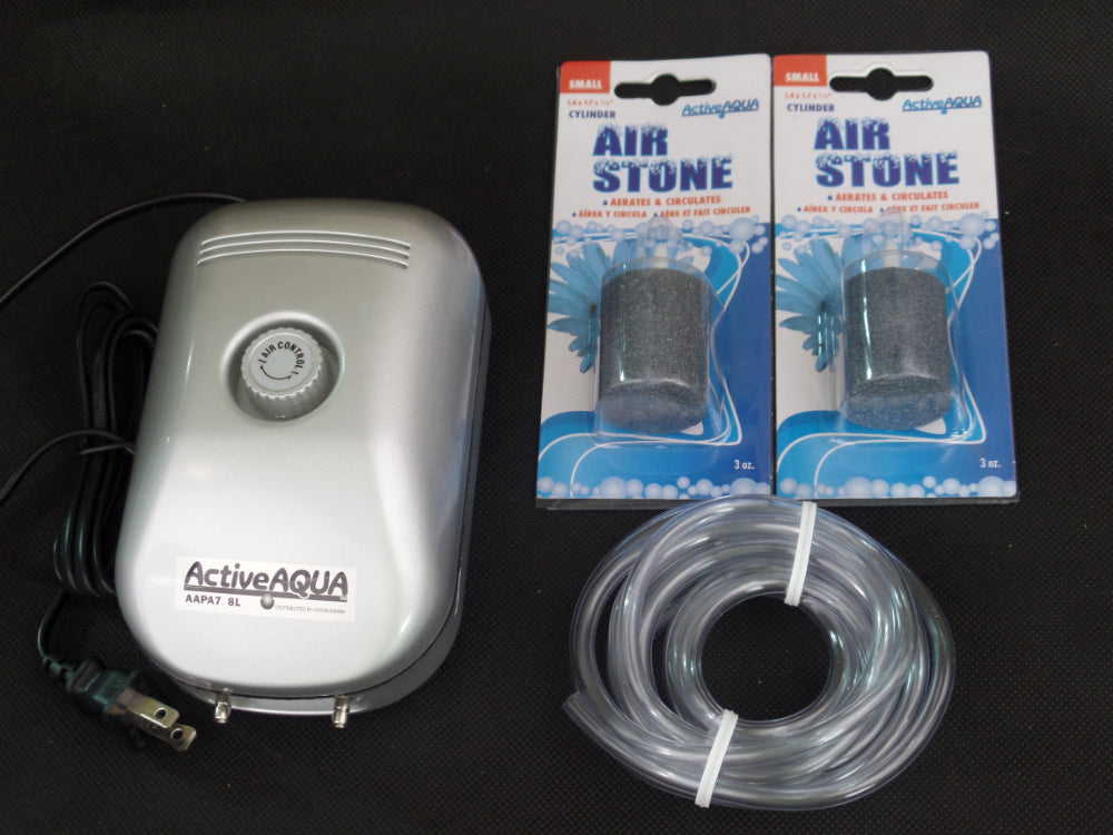 A TAS AquaAeration Kit with 2 Outlet Pump, packaged air stones, power cord, and clear tubing is displayed on a black surface—ideal for boosting decorative pond aeration.