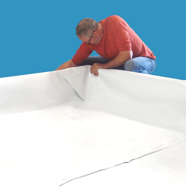A man laying out a durable sheet of agricultural-grade white plastic known as the Aquaponics For Life Dura-Skrim Liner – 12′ Width.