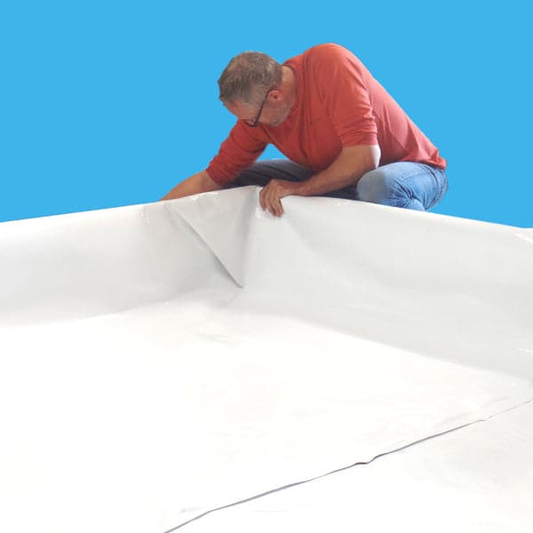 A man laying out a Dura-Skrim Liner – 6′ Width sheet of white cloth from Aquaponics For Life.