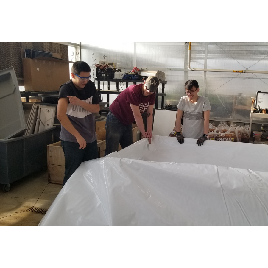 Three people standing around a large sheet of Aquaponics For Life Dura-Skrim Liner – 6&#39; Width.