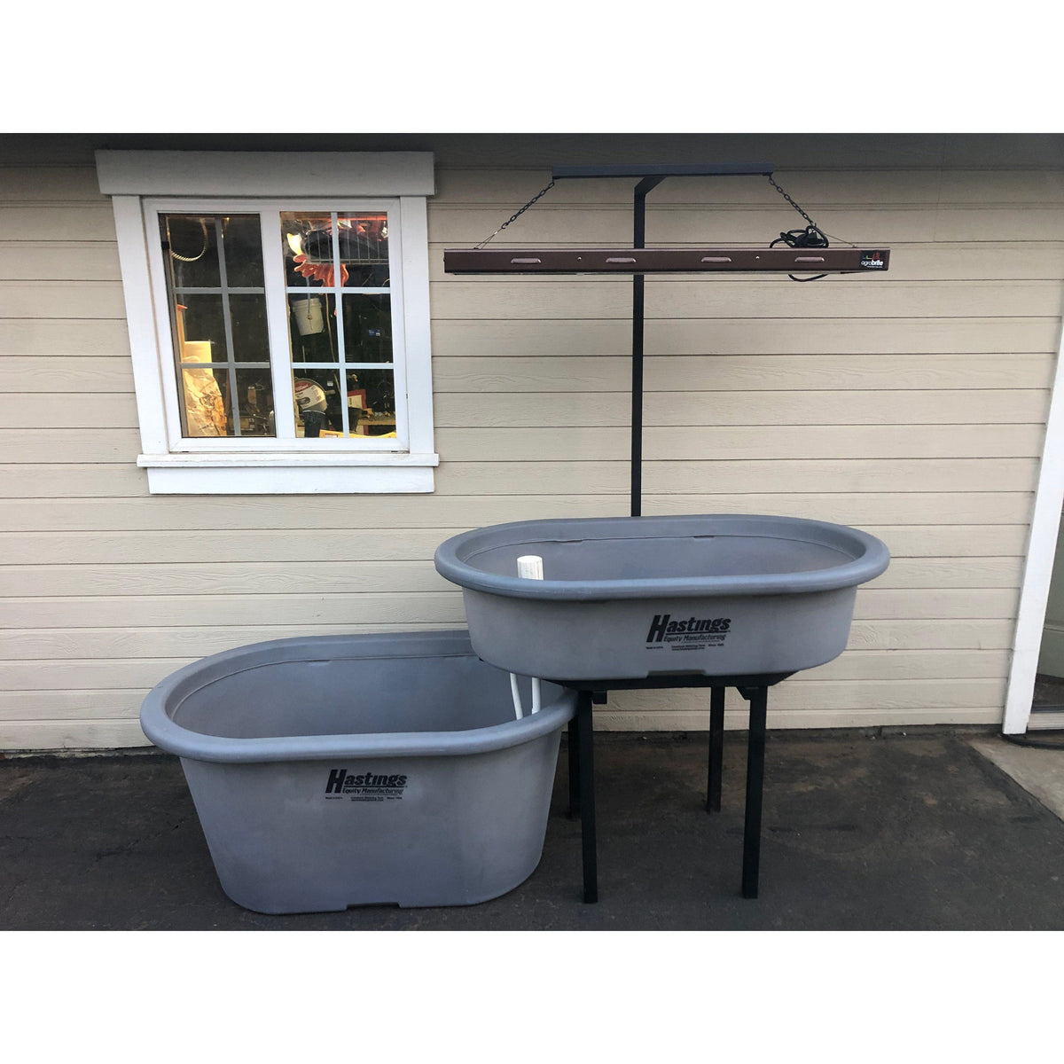 Two gray Go Green Aquaponics System tubs, resembling fish tanks, sitting outside of a house.